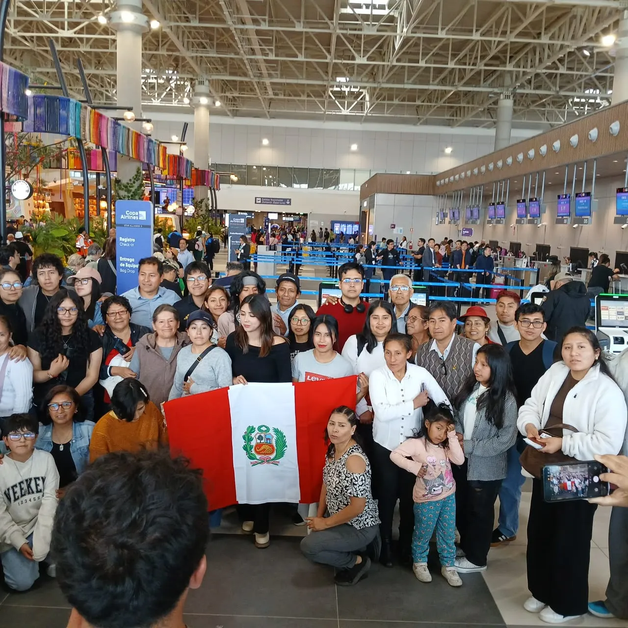 Estudiantes becados y sus familias con la bandera del Perú en el aeropuerto de Lima, antes de viajar a Rusia